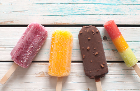 Assorted flavored ice lollies over a wooden backgroundの写真素材