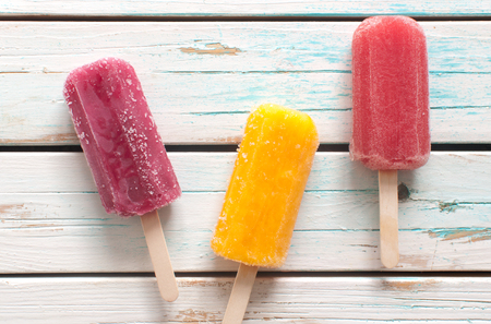 Assorted flavored ice lollies over a wooden backgroundの写真素材