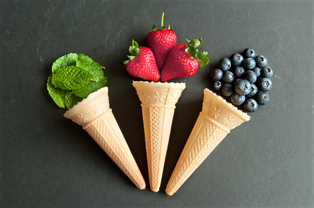Natural ingredients spilling out of an icecream cone including strawberry, mint and blueberriesの写真素材