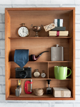 Fathers day gift with label inside a shelving unit with various objects including tools, camera and coffee cupの写真素材