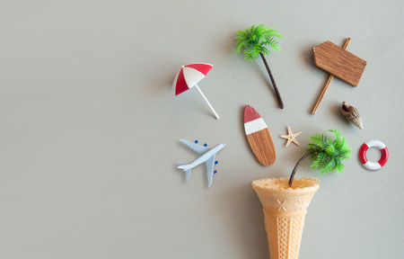 Icecream cone with various summer items including parasol, surfboard, miniature airplane and pine trees の写真素材