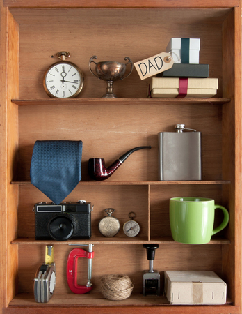 Fathers day gift with label inside a shelving unit with various objects including tools, camera and coffee cupの写真素材