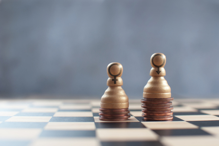 Two chess pawns on top of a heap of coins with varying heights の写真素材