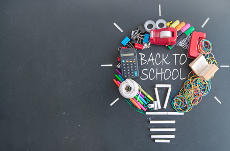 Light bulb icon made with many pieces of stationery on top of a chalkboardの写真素材