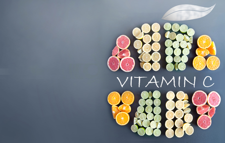 Many citrus fruits in the shape of a sliced fruit icon with vitamin c handwritten insideの写真素材