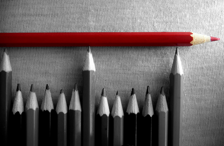 Red pencil on top of a group of pencils in black and whiteの写真素材