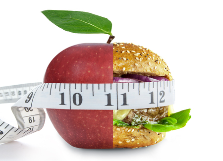 Tape measure aorund a healthy apple and unheatlhy burger merged into one over a white backgroundの写真素材