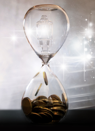 Light bulb inside an hourglass turning into moneyの写真素材