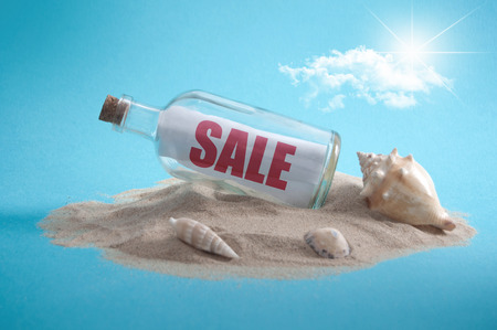 Sale sign inside a message bottle on a sandy islandの写真素材
