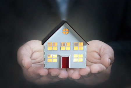 Business man holding a model house 