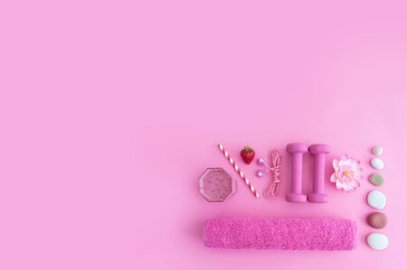 Health and excercise still life, including dumbbells, towel, and a berry smoothie with straw on a pink backgroundの写真素材