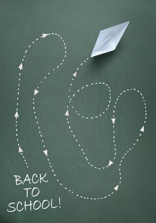 Back to school trail of a paper boat on chalkboardの写真素材