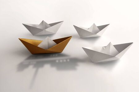 Gold paper boat with larger shadow of a cruise ship amongst other boatsの写真素材