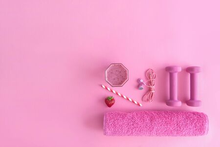 Health and excercise accessories, including dumbbells, towel, and a berry smoothie with straw on a pink backgroundの写真素材