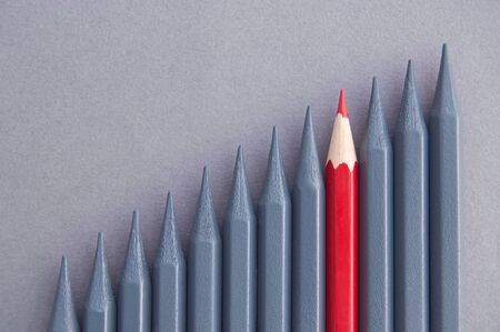 Red pencil in the middle standing out amongst greyed out pencilsの写真素材