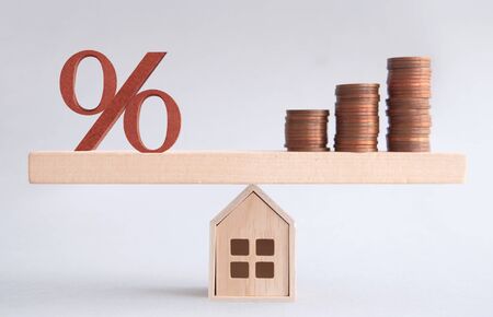 Percentage sign and stack of coins seasaw balanced on a miniature house, mortgage investment conceptの写真素材