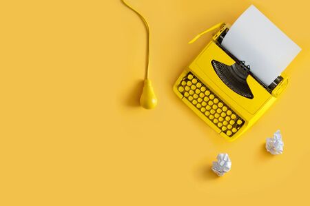 Orange retro typewriter on paper background with light bulb, brainstorming writers blockの写真素材