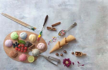 Assorted ice cream scoops on a painters palette with ingredients in the centre including strawberry and chocolateの写真素材