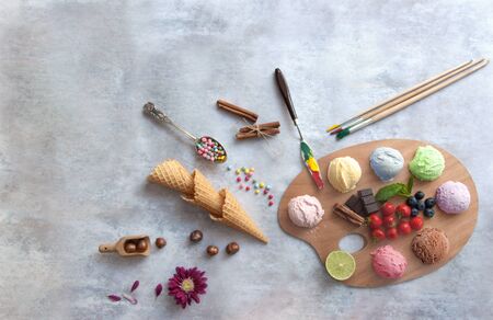 Assorted ice cream scoops on a painters palette with ingredients in the centre including strawberry and chocolateの写真素材
