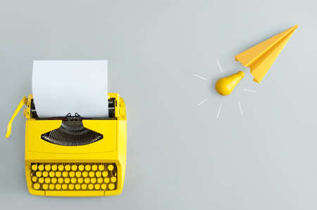 Retro typewriter with yellow paper airplane, and light bulb inspiration and innovationの写真素材
