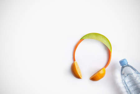 Headphones made of fruits including melon, carrots and oranges with water bottleの写真素材