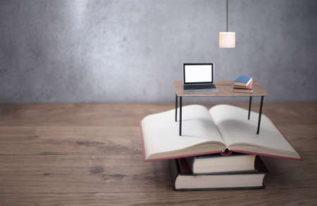 Miniature desk with laptop on top of open booksの写真素材