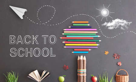 Back to school text on a chalkboard with paper airplane and tree made from stationery suppliesの写真素材