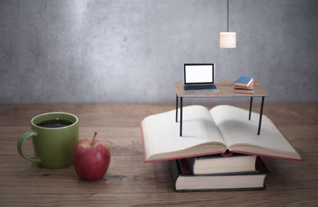 Miniature desk with laptop on top of open booksの写真素材