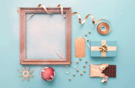 Decorative christmas blank picture frame covered in snow with gifts and wrapping accessoriesの写真素材