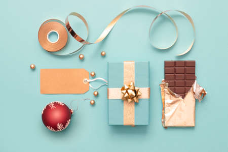 Top view of gift boxes wrapped in gold with baubles, wrapping accessories and chocolateの写真素材