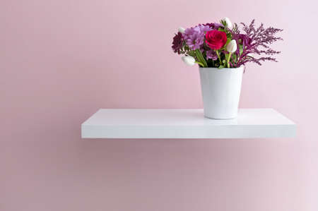 Seasonal flowers in a vase on a floating shelfの写真素材