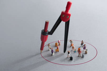 Compass with red pencil circle around miniature travellersの写真素材