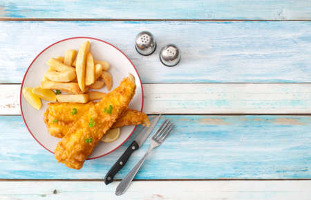 Deep fried cod with chips on a wooden tableの写真素材