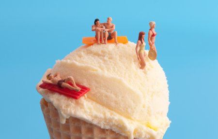 Miniature sunbathers on top of vanilla ice cream coneの写真素材