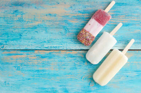Frozen assorted ice lollies on a wooden backgroundの写真素材
