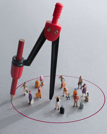 Compass with red pencil circle around miniature travellersの写真素材