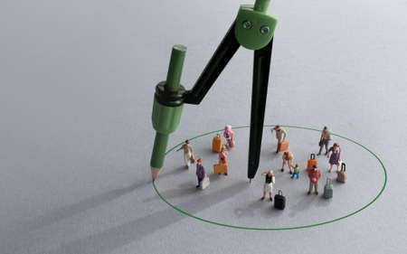 Compass with green pencil circle around miniature travellers representing restriction free zonesの写真素材