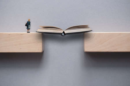 Open book bridging the gap between wooden blocks for female miniature figure to crossの写真素材
