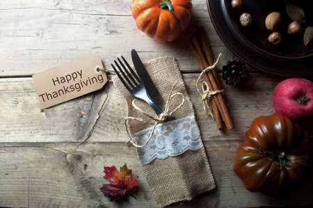 Thanksgiving greeting card attached to fork and knife on rustic wooden tableの写真素材