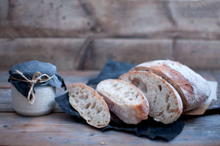 Sourdough bread slices next to a jar with live starter cultureの写真素材