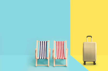 Cabin bag suitcase alongside two beach deck chairs with spaceの写真素材