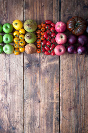 Selection of fruits and vegetables with rainbow colours on a rustic wooden background with space for textの写真素材