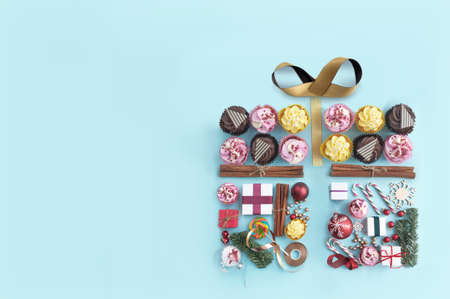 Collection of food confectionery and christmas decorations in the shape of a gift box with decorative gold ribbon bowの写真素材
