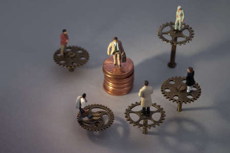Teamwork leadership concept, manager on coins surrounded by team of employees on cog wheelsの写真素材