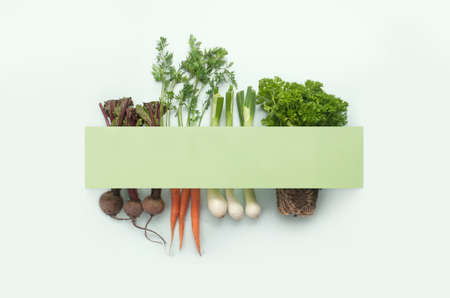 Vegetable roots and herbs underneath paper card with copy spaceの写真素材