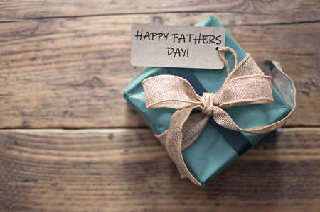 Fathers day greeting attached to gift box wrapped with a rustic ribbon bowの写真素材
