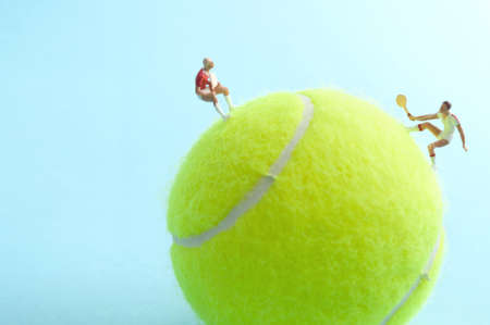 Two miniature tennis players on top of a ball competing in a matchの写真素材