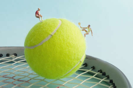 Miniature tennis players on tennis ball and racket playing matchの写真素材