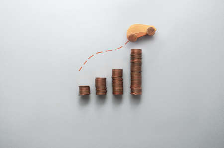 Increasing fuel, petrol, price concept, business chart stacks of coins with toy wooden car moving upwardsの写真素材