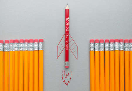Back to school red pencil with rocket sketch standing out amongst a row of orange pencilsの写真素材